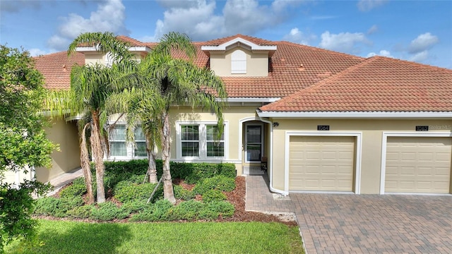 1064 Quaker Ridge Ln, Davenport, FL 33896 - mediterranean / spanish home featuring decorative driveway, an attached garage, a tiled roof, and stucco siding