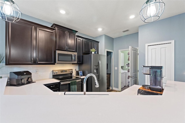 1064 Quaker Ridge Ln, Davenport, FL 33896 - kitchen with stainless steel appliances, decorative backsplash, light countertops, dark brown cabinetry, and decorative light fixtures
