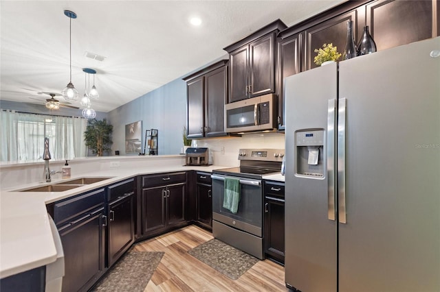 1064 Quaker Ridge Ln, Davenport, FL 33896 - kitchen with stainless steel appliances, a sink, light wood finished floors, light countertops, and decorative light fixtures