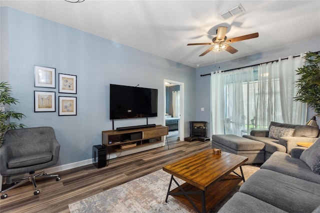 1064 Quaker Ridge Ln, Davenport, FL 33896 - living room with wood finished floors, ceiling fan, a wood stove, and baseboards