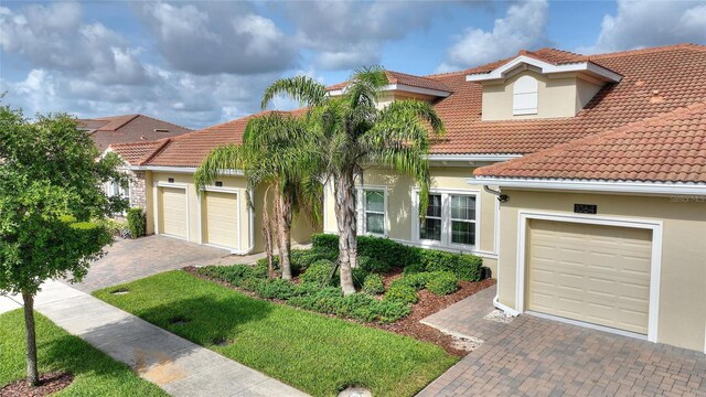 1064 Quaker Ridge Ln, Davenport, FL 33896 - mediterranean / spanish home featuring decorative driveway, a tiled roof, an attached garage, and stucco siding