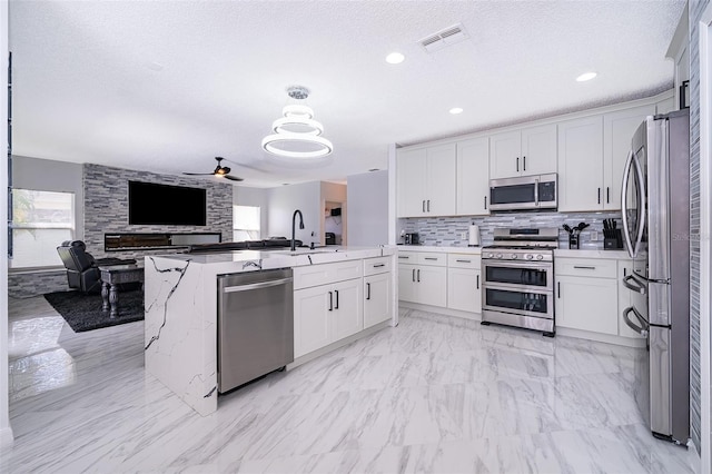 2503 Calla Lily Cv, Kissimmee, FL 34758 - kitchen featuring appliances with stainless steel finishes, ceiling fan, a sink, open floor plan, and white cabinetry