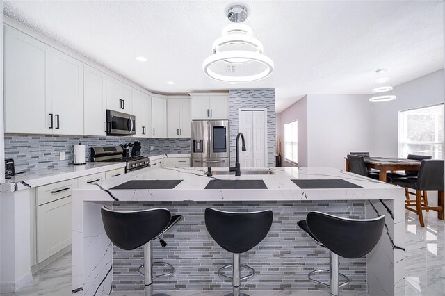 2503 Calla Lily Cv, Kissimmee, FL 34758 - kitchen with appliances with stainless steel finishes, light marble finish flooring, healthy amount of natural light, a breakfast bar area, and recessed lighting