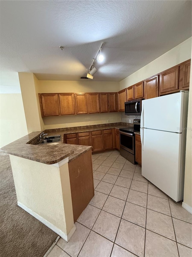 6169 Metrowest Blvd Unit 208, Orlando, FL 32835 - kitchen with appliances with stainless steel finishes, dark countertops, track lighting, a peninsula, and brown cabinets