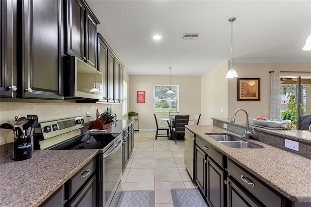 1353 Palmetto Dunes St, Davenport, FL 33836 - kitchen with stainless steel appliances, decorative light fixtures, light tile patterned floors, light stone countertops, and crown molding