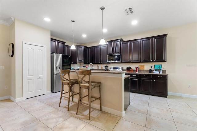 1353 Palmetto Dunes St, Davenport, FL 33836 - kitchen with appliances with stainless steel finishes, pendant lighting, a kitchen bar, a center island with sink, and light tile patterned floors
