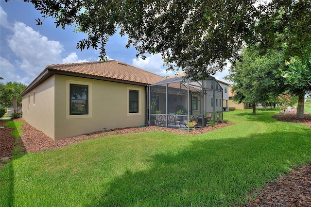1353 Palmetto Dunes St, Davenport, FL 33836 - rear view of house featuring a tiled roof, stucco siding, a lawn, and glass enclosure