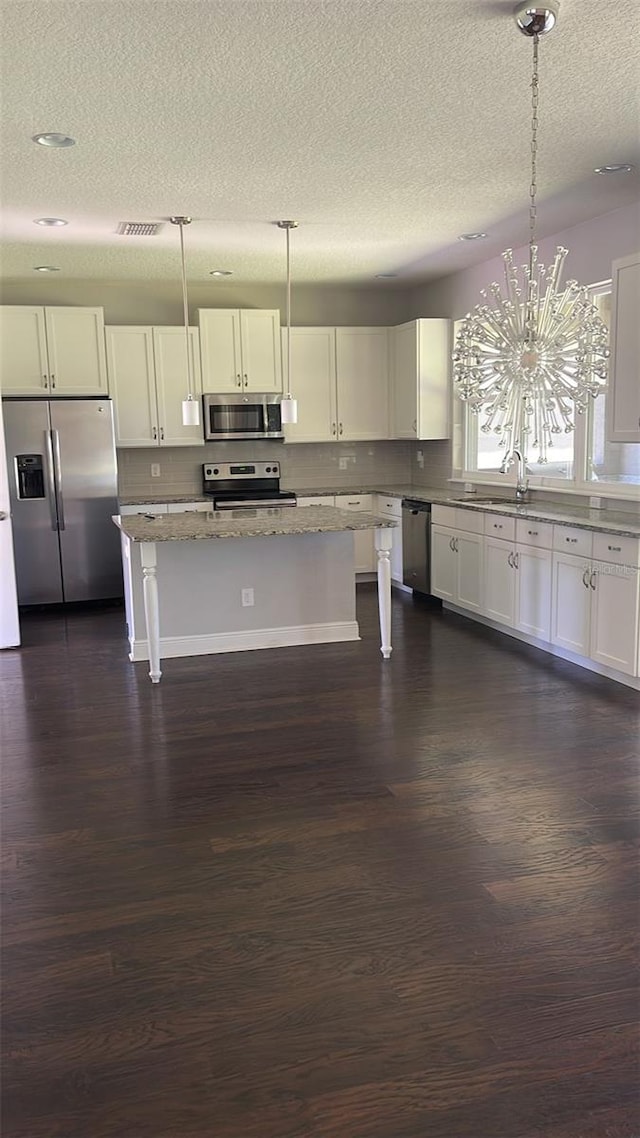 2813 Roseglen Way, Orlando, FL 32812 - kitchen with stainless steel appliances, a textured ceiling, dark wood-type flooring, light stone counters, and white cabinets