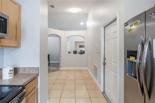 1659 Sage Creek Ct, Orlando, FL 32824 - kitchen with stainless steel appliances, light brown cabinetry, light tile patterned flooring, and arched walkways