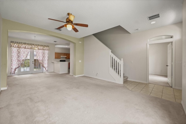 2050 Island Walk Dr, Orlando, FL 32824 - unfurnished living room with light colored carpet, ceiling fan, stairs, french doors, and arched walkways