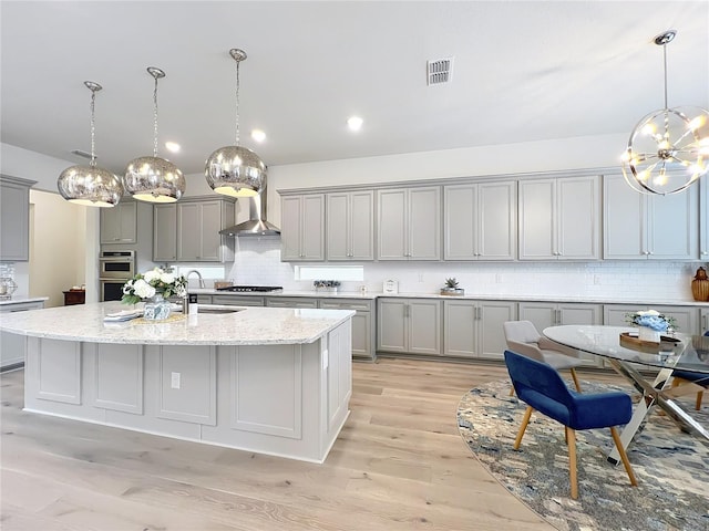 9071 Woodland Forest Rd, Orlando, FL 32836 - kitchen with gray cabinets, a chandelier, wall chimney range hood, and decorative backsplash