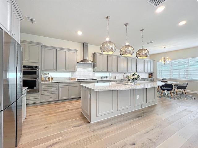 9071 Woodland Forest Rd, Orlando, FL 32836 - kitchen featuring wall chimney range hood, appliances with stainless steel finishes, gray cabinets, light wood-style floors, and backsplash