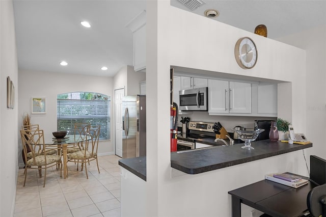 909 Troon Cir, Davenport, FL 33897 - kitchen with appliances with stainless steel finishes, dark countertops, light tile patterned flooring, white cabinetry, and a peninsula