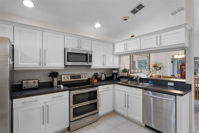 909 Troon Cir, Davenport, FL 33897 - kitchen with stainless steel appliances, dark countertops, white cabinets, light tile patterned floors, and recessed lighting