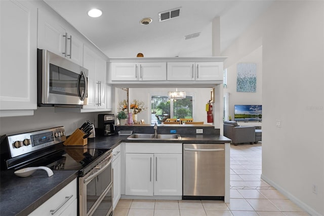 909 Troon Cir, Davenport, FL 33897 - kitchen with stainless steel appliances, dark countertops, white cabinets, light tile patterned floors, and recessed lighting