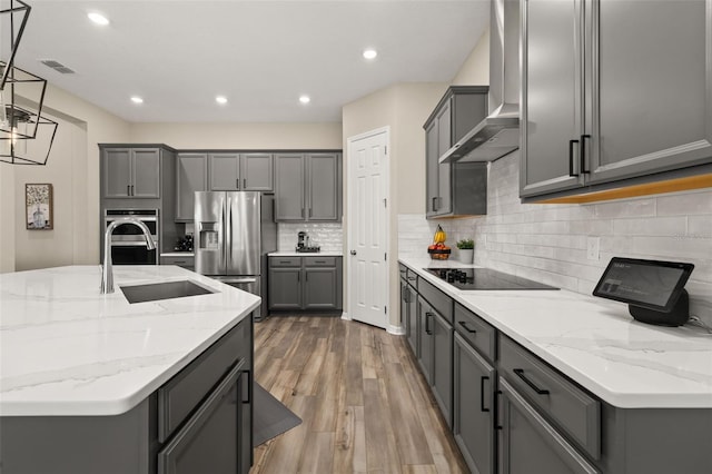 5133 Citrus Leaf Blvd, Winter Garden, FL 34787 - kitchen with stainless steel fridge, wall chimney range hood, gray cabinets, black electric stovetop, and wood finished floors