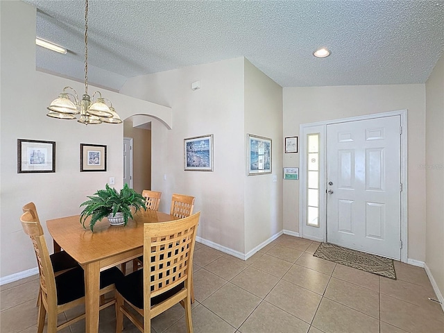 2649 Hemingway Ave, Haines City, FL 33844 - dining space with vaulted ceiling, a chandelier, a textured ceiling, light tile patterned floors, and arched walkways