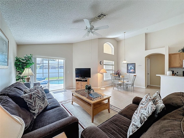 2649 Hemingway Ave, Haines City, FL 33844 - living area featuring arched walkways, light tile patterned floors, ceiling fan, high vaulted ceiling, and a textured ceiling