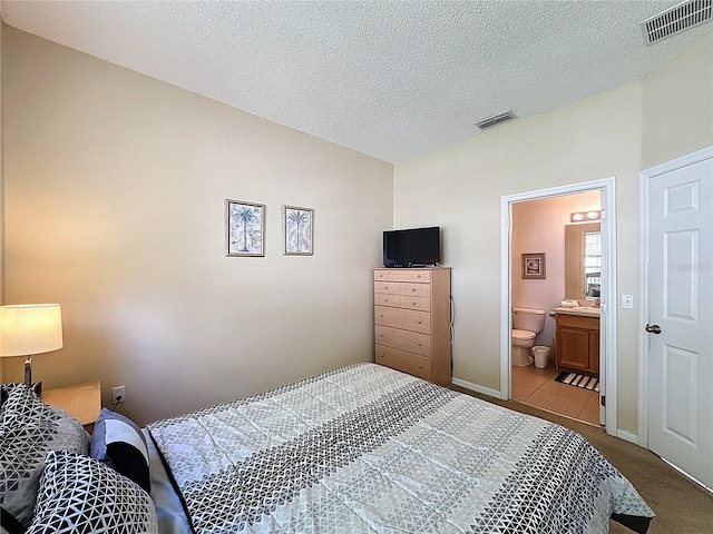 2649 Hemingway Ave, Haines City, FL 33844 - bedroom with ensuite bathroom, carpet flooring, tile patterned flooring, and a textured ceiling