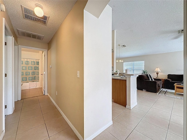 2649 Hemingway Ave, Haines City, FL 33844 - hall with a textured ceiling, light tile patterned floors, and a chandelier