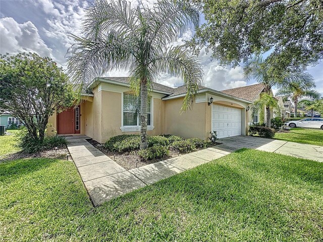 2649 Hemingway Ave, Haines City, FL 33844 - view of front of home featuring stucco siding, an attached garage, concrete driveway, and a front lawn