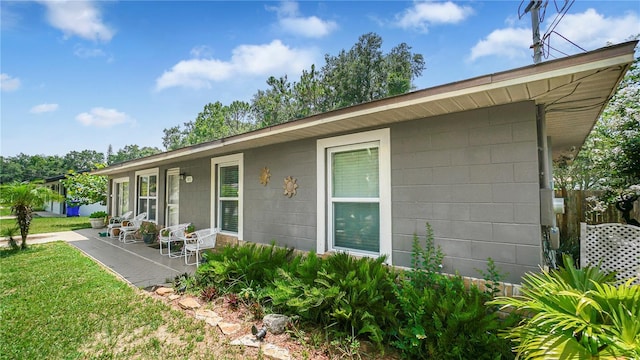 505 Oak Dr, Tavares, FL 32778 - view of side of property featuring concrete block siding, a lawn, and covered porch