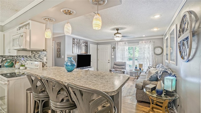 505 Oak Dr, Tavares, FL 32778 - kitchen featuring white appliances, a textured ceiling, crown molding, light wood-style flooring, and a peninsula