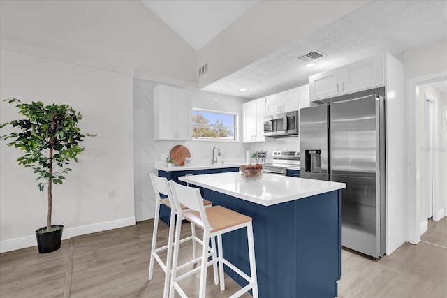 1501 Missouri Ave, Saint Cloud, FL 34769 - kitchen with appliances with stainless steel finishes, a kitchen breakfast bar, a kitchen island, white cabinets, and light countertops