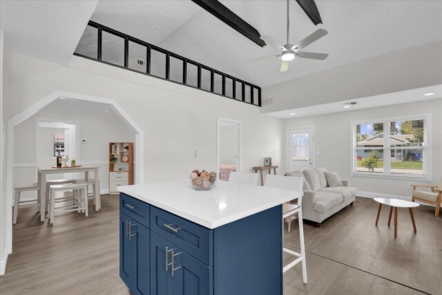 1501 Missouri Ave, Saint Cloud, FL 34769 - kitchen with blue cabinetry, a breakfast bar area, light wood-style flooring, a kitchen island, and ceiling fan