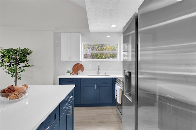 1501 Missouri Ave, Saint Cloud, FL 34769 - kitchen featuring stainless steel appliances, blue cabinets, light countertops, a textured ceiling, and white cabinetry