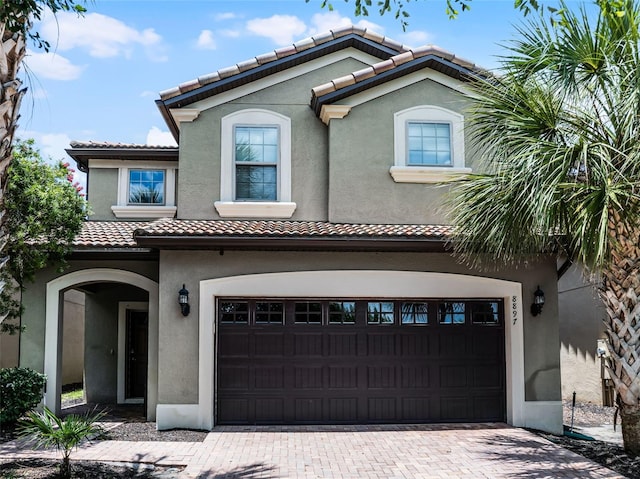 8897 Rhodes St, Kissimmee, FL 34747 - view of front of home featuring a tiled roof, an attached garage, stucco siding, and decorative driveway