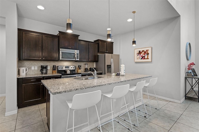 8897 Rhodes St, Kissimmee, FL 34747 - kitchen with stainless steel appliances, tasteful backsplash, a breakfast bar, light tile patterned flooring, and an island with sink