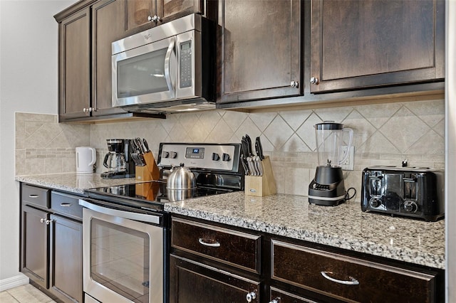 8897 Rhodes St, Kissimmee, FL 34747 - kitchen featuring appliances with stainless steel finishes, dark brown cabinetry, light stone counters, and decorative backsplash