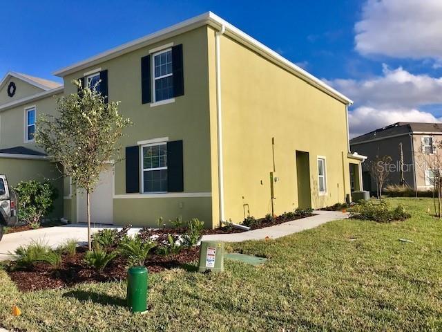 403 Arbor Lakes Dr, Davenport, FL 33896 - view of side of home featuring stucco siding, a yard, a garage, and driveway