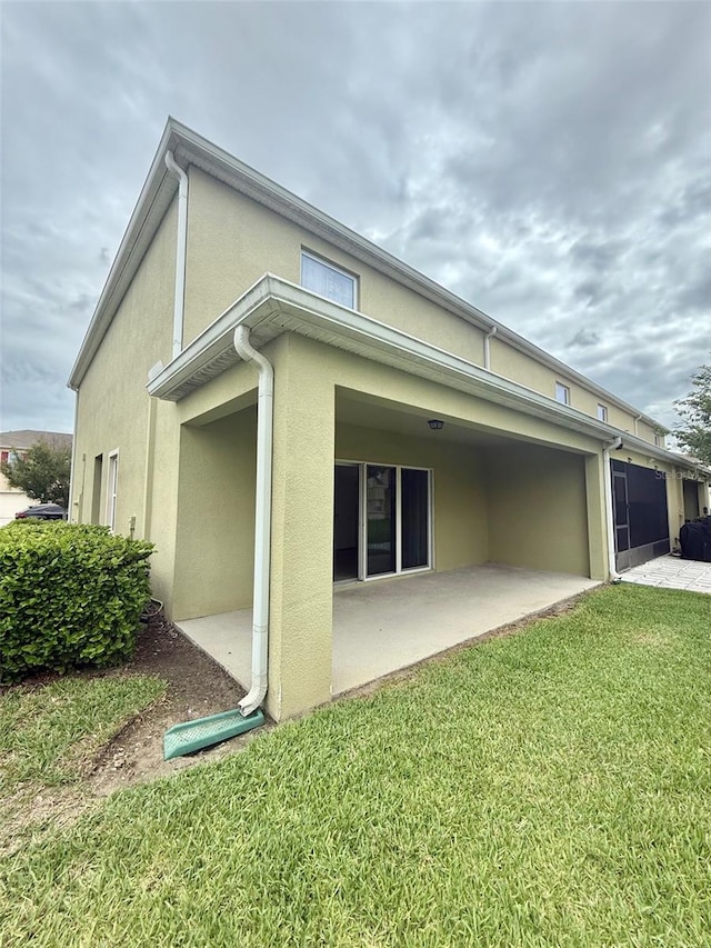 403 Arbor Lakes Dr, Davenport, FL 33896 - back of house with stucco siding, a patio area, and a lawn