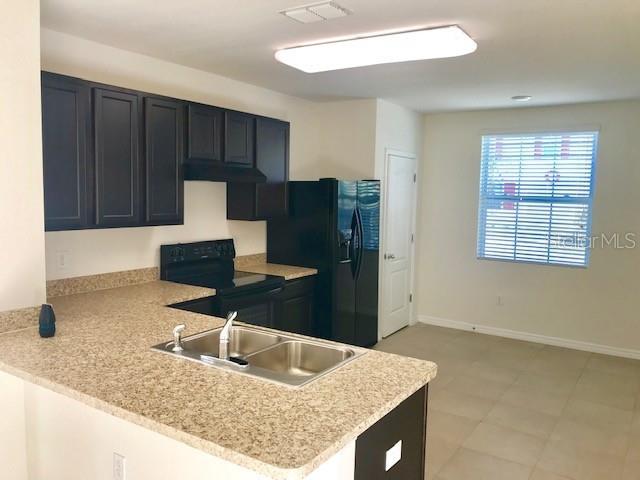 403 Arbor Lakes Dr, Davenport, FL 33896 - kitchen featuring black appliances, under cabinet range hood, light countertops, a peninsula, and dark cabinets