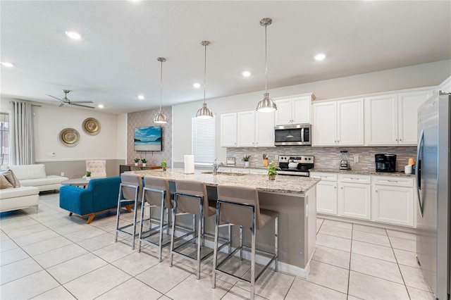 2161 Lelani Cir, Davenport, FL 33897 - kitchen with appliances with stainless steel finishes, light tile patterned floors, open floor plan, decorative backsplash, and a kitchen bar