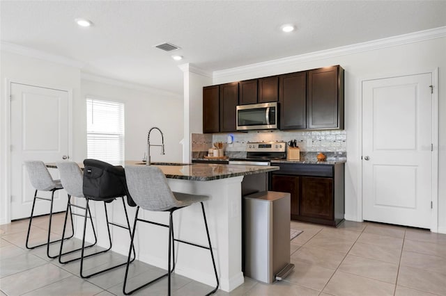 3255 Hilltop Cir, Bradenton, FL 34211 - kitchen with appliances with stainless steel finishes, a kitchen breakfast bar, crown molding, tasteful backsplash, and a center island with sink