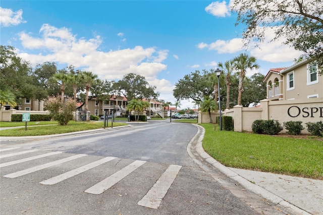 2832 Osprey Cove Pl Unit 102, Kissimmee, FL 34746 - view of asphalt road with curbs, street lighting, a residential view, a gated entry, and a gate