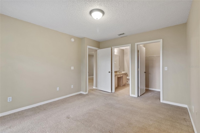 2832 Osprey Cove Pl Unit 102, Kissimmee, FL 34746 - unfurnished bedroom with light carpet, a spacious closet, a textured ceiling, a closet, and ensuite bathroom
