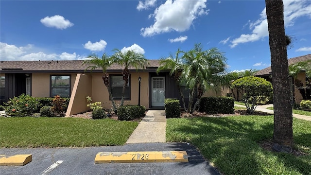 2326 St Marteen Ct, Kissimmee, FL 34741 - view of front of house with stucco siding, a front lawn, and uncovered parking
