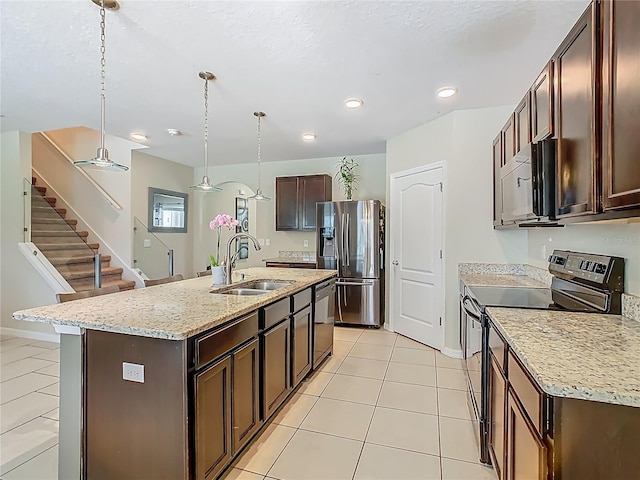 209 Willow Bend Dr, Davenport, FL 33897 - kitchen featuring stainless steel appliances, decorative light fixtures, dark brown cabinetry, an island with sink, and recessed lighting