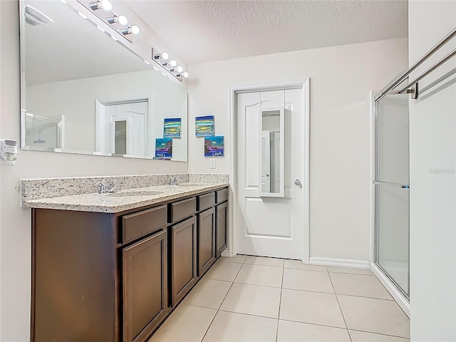 209 Willow Bend Dr, Davenport, FL 33897 - bathroom with double vanity, tile patterned floors, a textured ceiling, and a shower with shower door