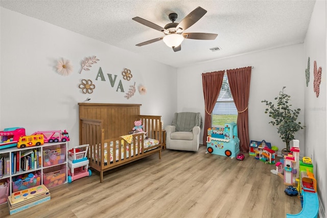 138 Hidden Pointe Ln, Groveland, FL 34736 - bedroom with wood finished floors, a crib, a textured ceiling, and ceiling fan