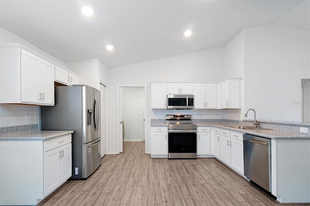 4505 Hummingbird Ln, Haines City, FL 33844 - kitchen with stainless steel appliances, lofted ceiling, tasteful backsplash, light wood-type flooring, and white cabinets