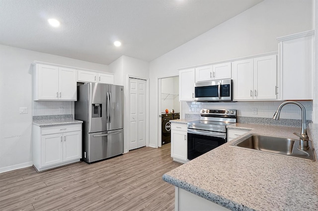 4505 Hummingbird Ln, Haines City, FL 33844 - kitchen with appliances with stainless steel finishes, white cabinetry, backsplash, vaulted ceiling, and light wood-style floors