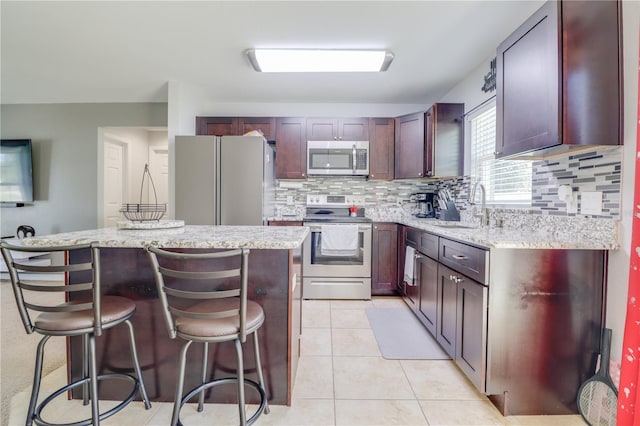 10 Pine Track Trl, Ocala, FL 34472 - kitchen with appliances with stainless steel finishes, a center island, decorative backsplash, a kitchen bar, and light stone countertops