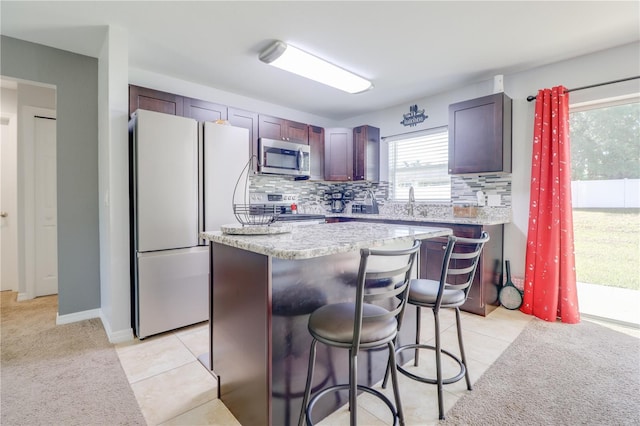 10 Pine Track Trl, Ocala, FL 34472 - kitchen featuring stainless steel appliances, a breakfast bar area, backsplash, a center island, and light tile patterned floors