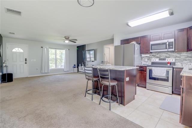 10 Pine Track Trl, Ocala, FL 34472 - kitchen with stainless steel appliances, a breakfast bar, a kitchen island, a ceiling fan, and tasteful backsplash