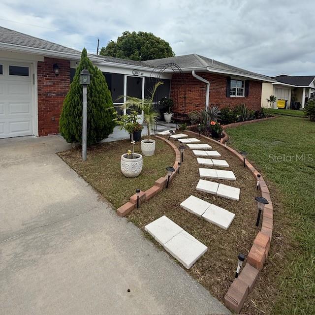 2013 Marilyn Ave, Winter Haven, FL 33881 - view of front of home with brick siding, a front lawn, concrete driveway, and roof with shingles